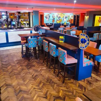 a bar with wooden tables and chairs in a restaurant at The Hydro Hotel in Douglas