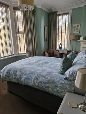 a bedroom with a large bed with blue walls and windows at Warwick Lodge in Carlisle