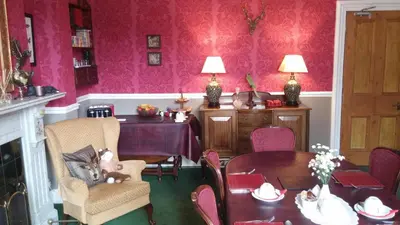 a dining room with pink walls and a table and chairs at Warwick Lodge in Carlisle
