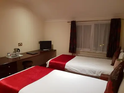 a hotel room with two beds and a desk at Ascot Hotel in Douglas