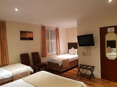 a hotel room with two beds and a flat screen tv at Ascot Hotel in Douglas