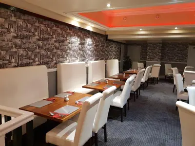a dining room with wooden tables and white chairs at Ascot Hotel in Douglas