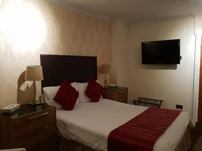 a hotel room with a bed and a flat screen tv at Ascot Hotel in Douglas