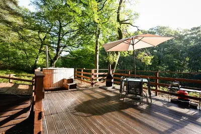 a wooden deck with a table and an umbrella at Broomhills Farm River Eco Pods in Carlisle