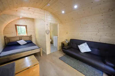 a living room with a couch in a wooden room at Broomhills Farm River Eco Pods in Carlisle