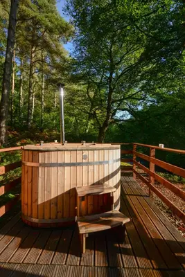 a wooden hot tub sitting on a wooden deck at Broomhills Farm River Eco Pods in Carlisle