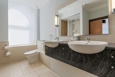 a bathroom with two sinks and a toilet and a mirror at Claremont Hotel in Douglas