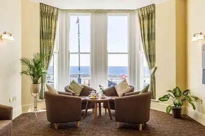 a living room with a couch and a table and windows at The Rutland Hotel in Douglas