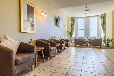 a waiting room with chairs and a table and windows at The Rutland Hotel in Douglas