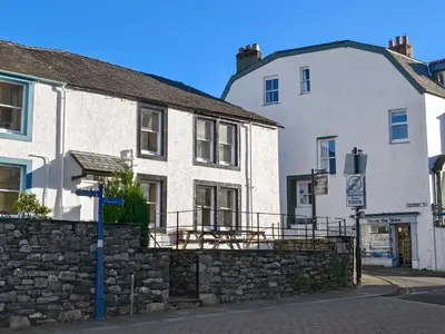 a couple of white buildings next to a stone wall at Rose Patch Cottage in Keswick