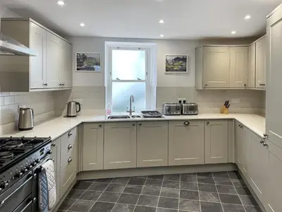 a kitchen with white cabinets and a window at Rose Patch Cottage in Keswick