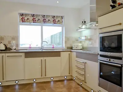 a kitchen with white cabinets and a window and a sink at Cobble Garth in Keswick