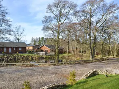 a house with a stone fence and a driveway at Larchwood in Ellonby