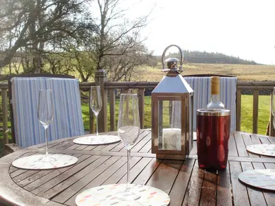 a wooden table with wine glasses and a lantern at Larchwood in Ellonby