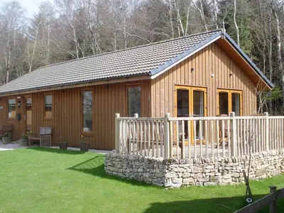 a large wooden cabin with a stone wall at Larchwood in Ellonby