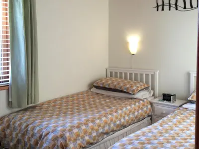 a bedroom with two beds and a lamp on the wall at Larchwood in Ellonby