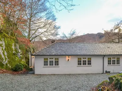 a white house with a gravel driveway at The Coach House in Grasmere