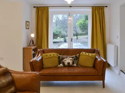 a dog laying on a couch in a living room at The Coach House in Grasmere