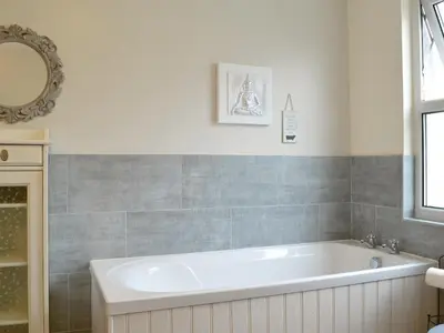 a white bath tub in a bathroom with a mirror at Hawthorne House in Bassenthwaite Lake