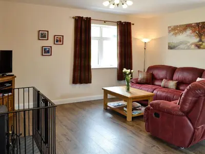 a living room with a red couch and a table at Liftingstane Cottage in Closeburn