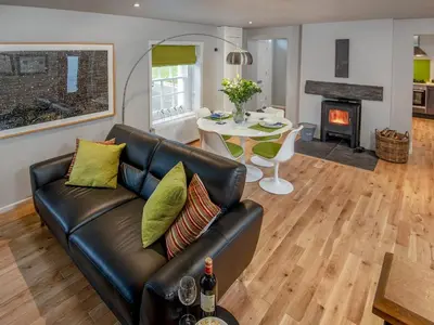 a living room with a leather couch and a table at Granary in Gatehouse of Fleet