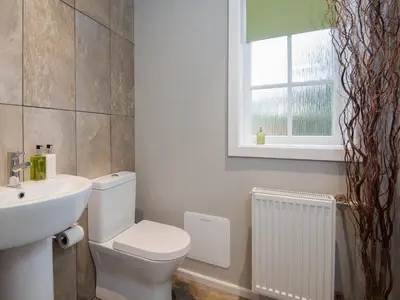 a bathroom with a toilet and a sink and a window at Granary in Gatehouse of Fleet