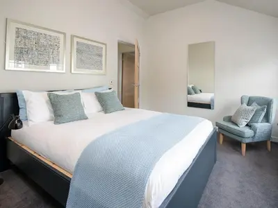 a bedroom with a large bed and a chair at Knocktinkle in Gatehouse of Fleet