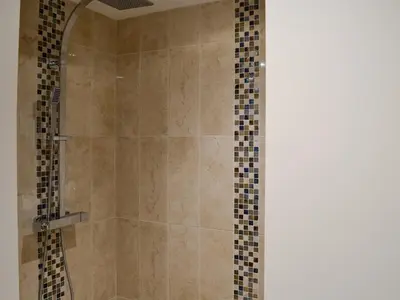 a bathroom with a shower with tiled walls at The Wheat Shed in Calthwaite