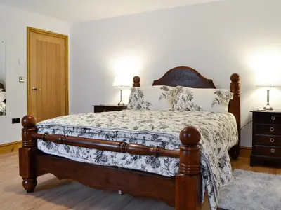 a bedroom with a bed and two night stands with lamps at The Wheat Shed in Calthwaite