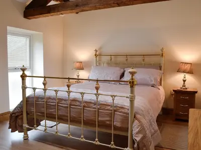 a bedroom with a metal bed with two lamps at The Wheat Shed in Calthwaite