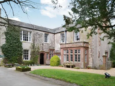 a large stone house with a yard in front of it at Blaithwaite House in Blencogo