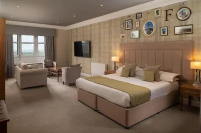 a bedroom with a large bed and a living room at Fairfield House Hotel in Ayr