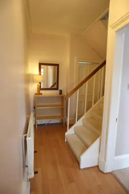 a hallway with a staircase with a mirror and a table at Ayrshire cottage in Kilmarnock