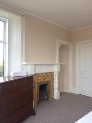 a bedroom with a fireplace and a dresser and a bed at Ayrshire cottage in Kilmarnock