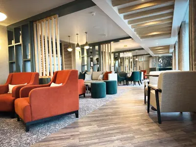 a waiting room with orange chairs and tables at Smiths At Gretna Green Hotel in Gretna Green