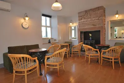a room with chairs and tables and a fireplace at The Lion and The Lamb in Seascale