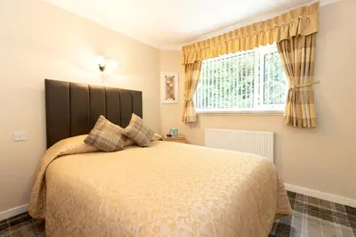 a bedroom with a large bed and a window at The Hill Hotel in Dumfries