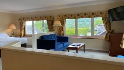 a hotel room with a bed and a blue chair at Lake District Castle Inn Hotel & Spa in Keswick