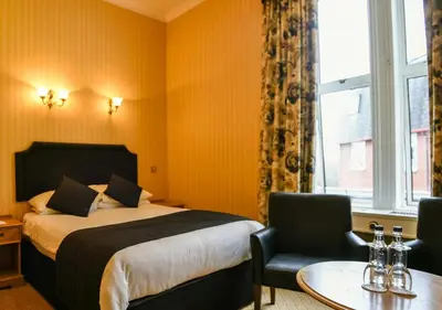 a hotel room with a bed and a table and chairs at Cairndale Hotel & Spa in Dumfries