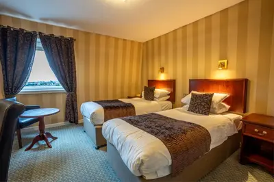 a hotel room with two beds and a window at Cairndale Hotel & Spa in Dumfries