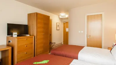 a bedroom with a bed and a dresser with a television at Holiday Inn Dumfries by IHG in Dumfries