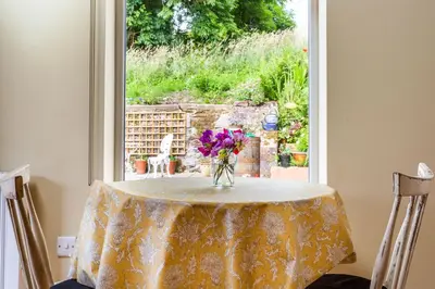 a vase of flowers sitting on a table in front of a window at Cruickshanks Boutique B&B in Whiting Bay