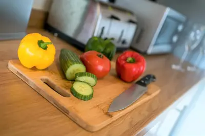 a cutting board with vegetables and a knife on a counter at Wordsworth Apartment Irene court in Cockermouth