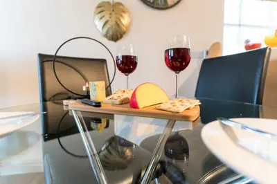 two glasses of red wine and cheese on a table at Wordsworth Apartment Irene court in Cockermouth