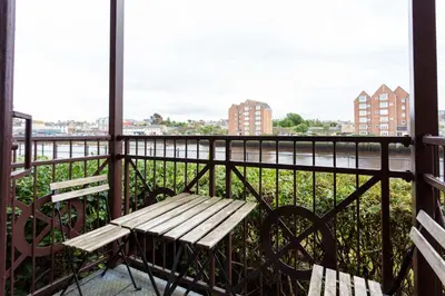 a bench sitting on a balcony looking out at the water at Harbour House - Donnini Apartments in Ayr