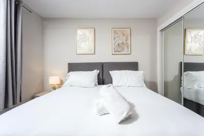a bedroom with a large white bed with white pillows at Harbour House - Donnini Apartments in Ayr