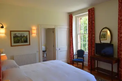 a bedroom with a bed and a television and a chair at Warwick Hall in Carlisle