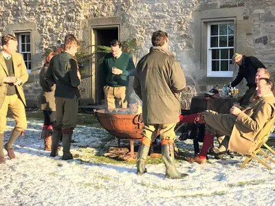 a group of men standing around a table in the snow at Carnell Country Estate & Holiday Cottages in Ayrshire in Hurlford