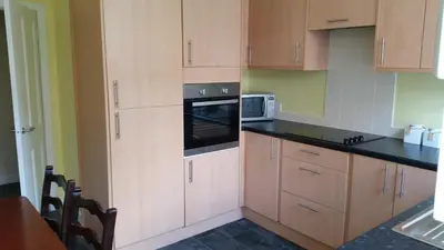a kitchen with wooden cabinets and a microwave at Central Dumfries in Dumfries
