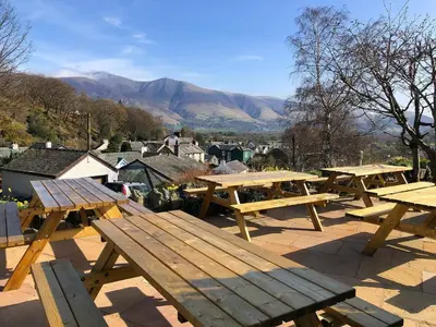 a group of picnic tables with mountains in the background at The Coledale Inn in Keswick